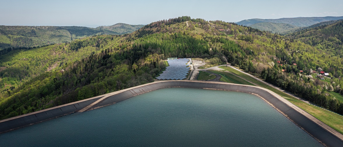 Zbiornik wodny otoczony lasami i polami, symbolizujący zrównoważony rozwój.