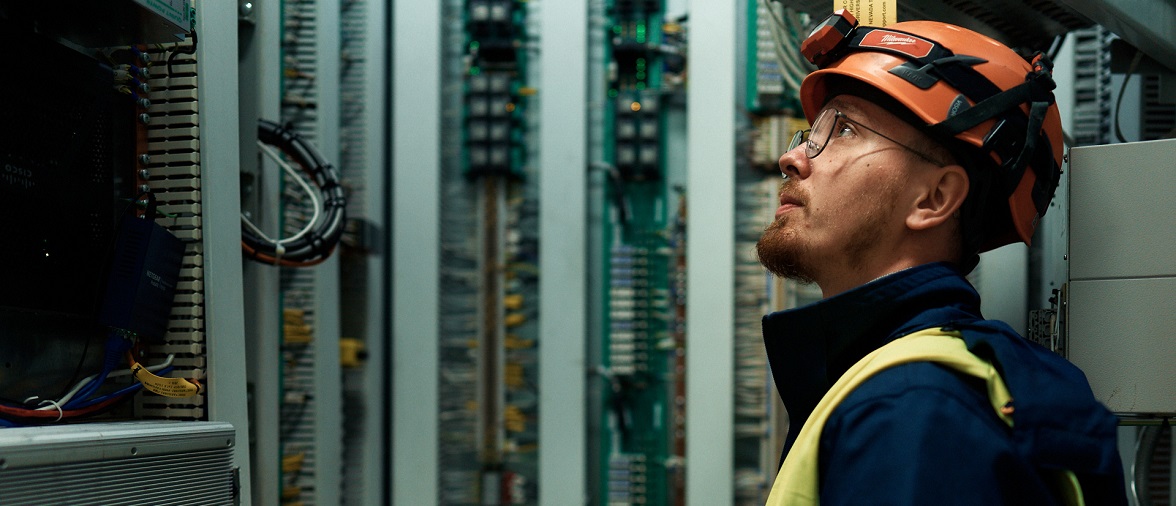 Mężczyzna patrzy na urządzenie techniczne, symbolizując karierę w PGE.